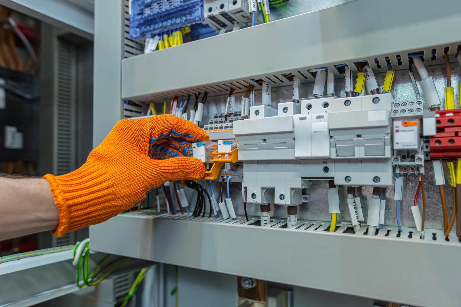 Hand of male electrical engineer mounts power energy shields close up photo
